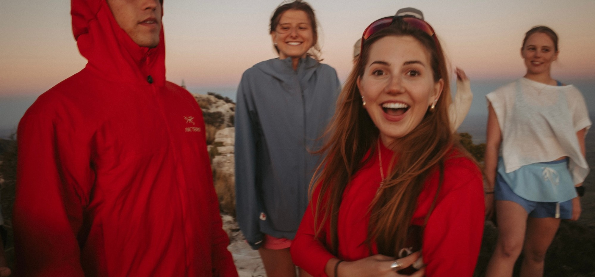 Anabelle laughing with friends on a mountaintop at sunset